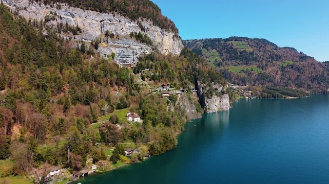 Aerial: Lake Thun and Saint Beatus Caves during the day below Beatenberg in canton of Bern, Switzerland, orbit drone shot