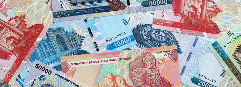 Uzbekistani som money banknotes pile on table. Uzbekistan bills of UZS currency close up