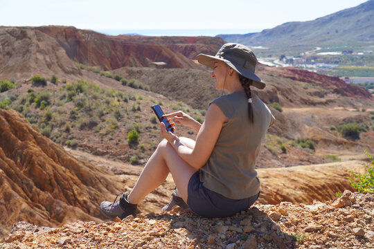 technology and outdoor adventure. middle-aged woman on a day of trakking with her smartphone checking the route or taking photos