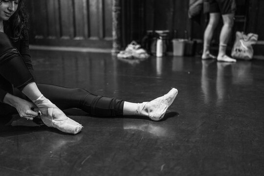 Ballerina preparing pointe shoes for ballet performance