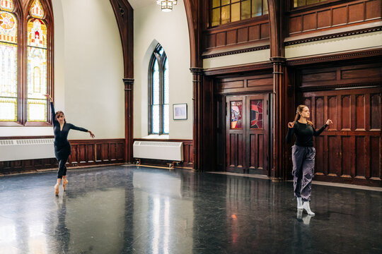 Two dancers rehearsing in grand studio with stained glass windows