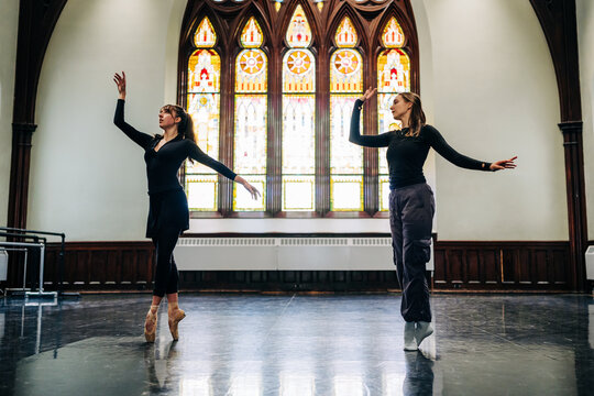 Ballerinas practicing ballet in an old hall with stained glass