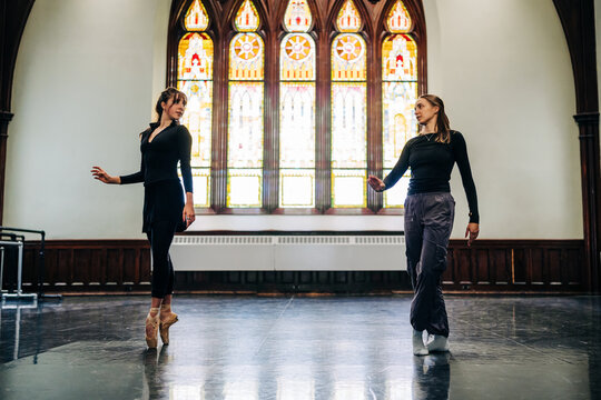 Ballet dancers rehearsing in grand studio with stained glass