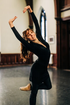 Smiling ballerina posing gracefully in dance studio