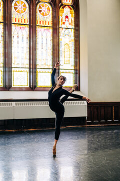 Ballerina posing on pointe in front of stained glass window
