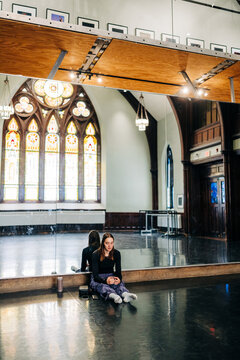 Woman reflecting in dance studio stained glass light