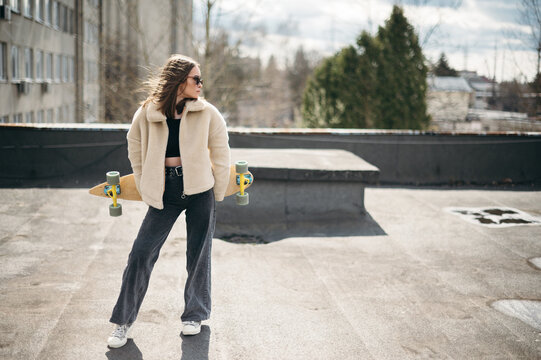 Young woman with a skateboard on a rooftop in urban setting
