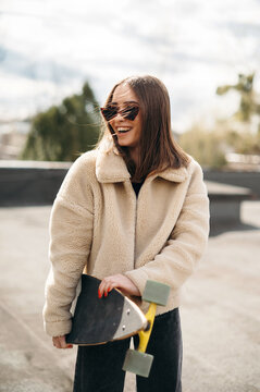 Smiling woman standing on roof with skateboard in hands