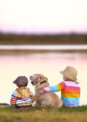 cute children with their dog sitting on a meadow near the sea © Jenny Sturm