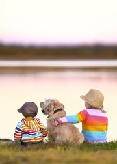 cute children with their dog sitting on a meadow near the sea © Jenny Sturm