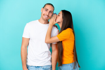 Naklejka premium Young caucasian couple isolated on blue background whispering something