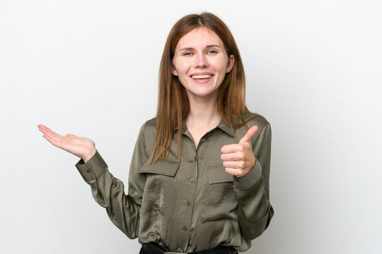 Young English woman isolated on white background holding copyspace imaginary on the palm to insert an ad and with thumbs up