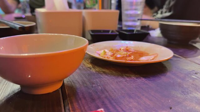 Chopsticks picking food from dipping sauce at a lively Hoi An dinner table, capturing casual shared dining, warm restaurant atmosphere, and candid Vietnam food culture.