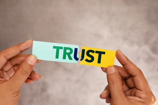 Hands tearing paper with word trust, broken relationship concept, trust issues