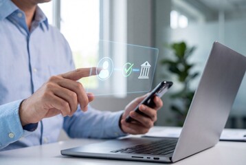 Obraz premium Businessman using smartphone and laptop with digital banking verification interface in modern office
