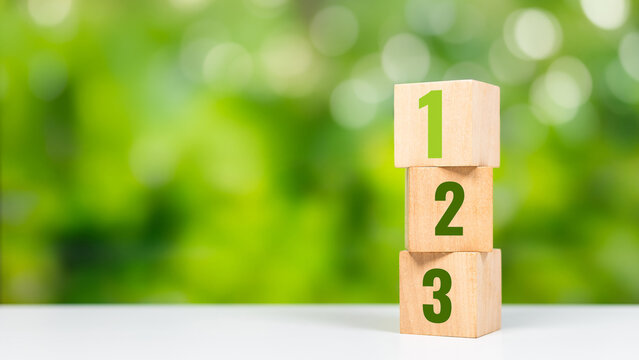 Vertical stack of wooden blocks with numbers 1, 2, 3 showing step growth or ranking. Step growth and ranking concept with stacked number blocks