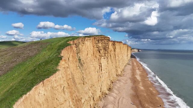 Sandstone sea cliffs West Bay Dorset UK dramatic sky drone aerial view