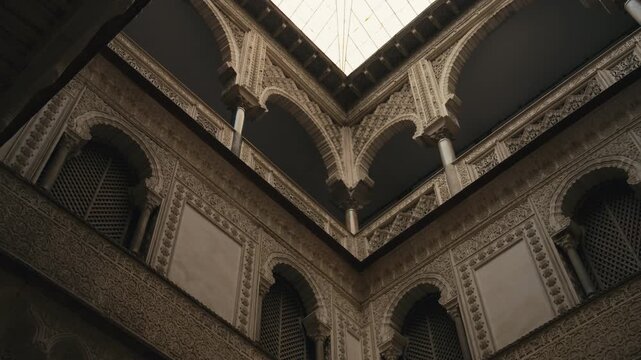 Close-up view of intricate Moorish architecture inside Real Alc&aacute;zar in Seville, Spain, showcasing ornate arches, detailed carvings, and historic interior design.