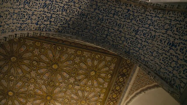 Close-up of intricate Moorish patterns and geometric ceiling details inside Real Alc&aacute;zar in Seville, Spain, highlighting craftsmanship and historic design.