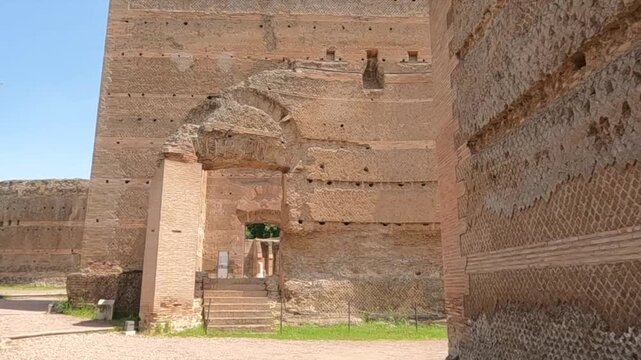 Massive ancient Roman brick walls and arched gateway at Villa Adriana, Hadrian's Villa near Tivoli, Italy. UNESCO World Heritage Site with weathered stone ruins under blue sky.