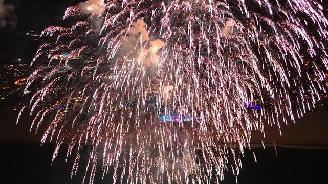 4K drone capturing a massive finale firework explosion over a beach concert in San Jos&eacute; del Cabo, with the illuminated cityscape in the background.
