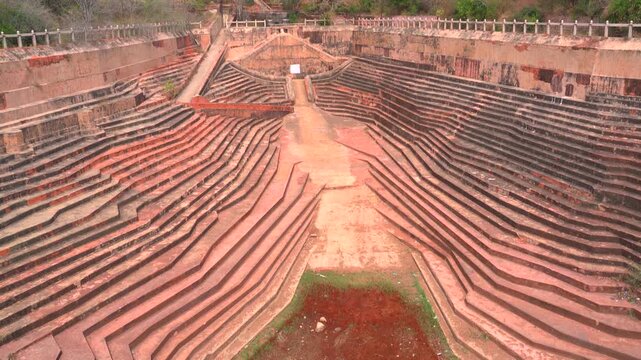 A high-angle static shot showcasing the symmetrical zigzag stone steps and historical water reservoir at the Nahargarh Fort stepwell.