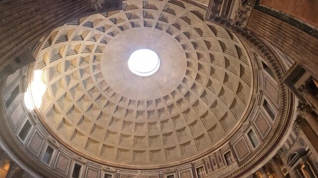 Upward view of the Pantheon's iconic coffered dome and central oculus in Rome, Italy. Natural light streams through the opening of this ancient Roman architectural marvel.
