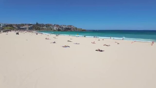 Bondi Beach Sydney Australia crowded sunny coastline with relaxing people sunbathing lying on sand ocean waves cinematic pan walking tour