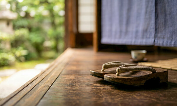 Traditional Japanese wooden geta sandals on a wooden porch overlooking a blurred green garden