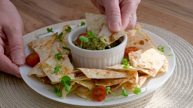 Hand dipping crispy chips into fresh guacamole video
