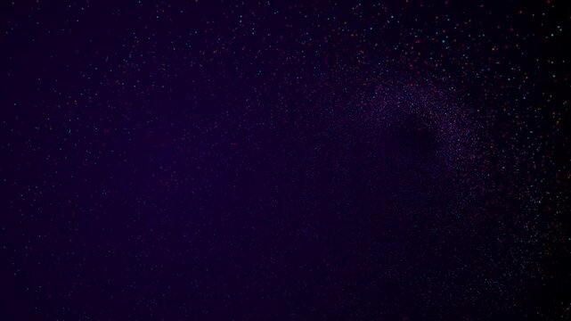 Abstract dark background with scattered colorful glowing particles and stardust effect