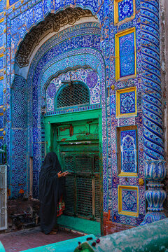 A devotee praying at the shrine of Multan with decorated Blue tiles
