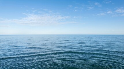 Obraz premium Vast blue ocean under a clear sky, with gentle ripples on the water's surface, conveying a sense of tranquility and endlessness