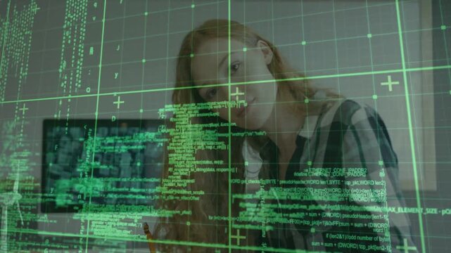 Woman writing at desk noticing monitor previews, raising head and checking code HUD in technology