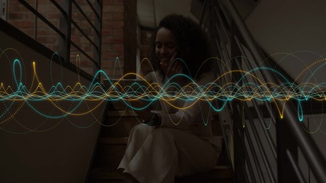Woman sitting on stairs tapping device and shifting waveform while previewing audio for marketing