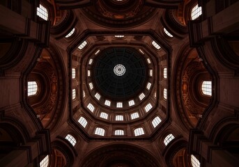 Obraz premium Majestic architectural perspective looking upward through a grand, ornate dome featuring repeating arched windows and intricate structural elements bathed in warm, ambient light