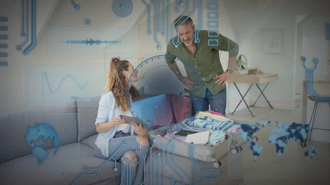 Woman on sofa tapping tablet, man leaning over suitcase pointing, blue trip overlay showing packing