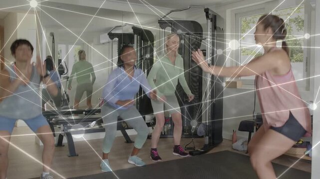 Vertical video: Gesturing coach guiding 3 women in gear doing squats training in home gym, overlay