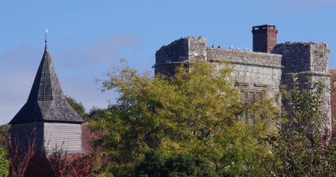 Wide panning shot left to right of St Mary and St Peter's Church tower with fortified house tower