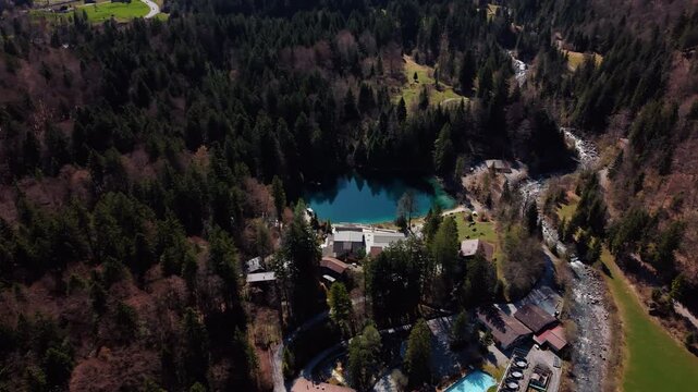Aerial: Blausee and Kander river in Bernese Oberland during the day in Kandergrund, canton of Bern, Switzerland, orbit drone shot
