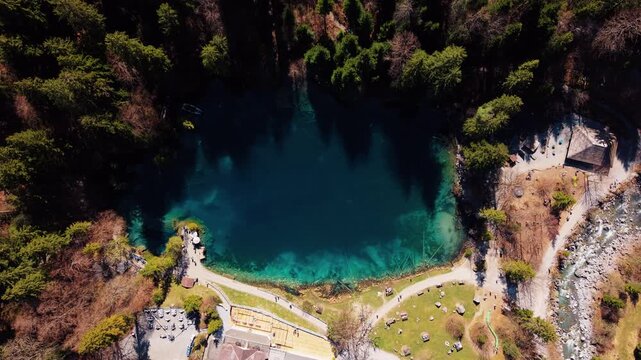 Aerial: Blausee in Bernese Oberland during the day in Kandergrund, canton of Bern, Switzerland, long slow pull-in drone shot