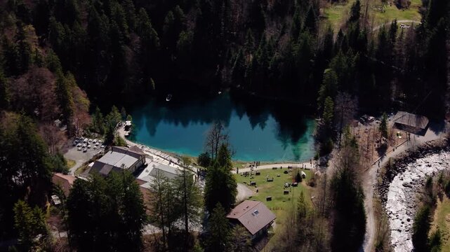 Aerial: close up shot of Blausee and Kander river in Bernese Oberland during the day in Kandergrund, canton of Bern, Switzerland, orbit drone shot