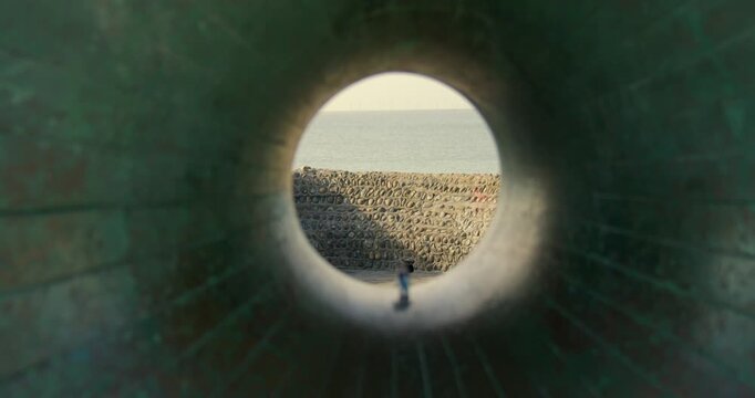 shot looking through the hole of the Afloat Sculpture with the beach. On Brighton beach next to Brighton pier