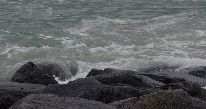 Mid shot of sea breaking over rock groyne on Shoreham beach.