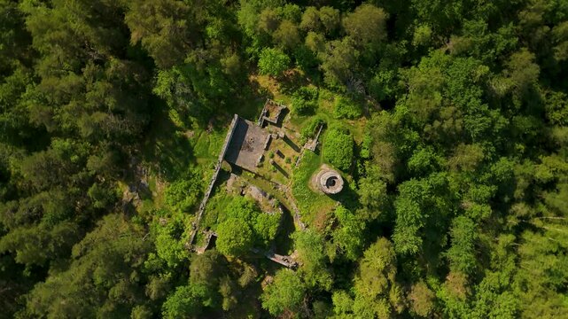 Aerial top-down drone spin above Tureborgs Slott medieval castle ruins surrounded by dense green forest in Sweden