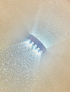 Modern LED wall sconce casting light on textured plaster