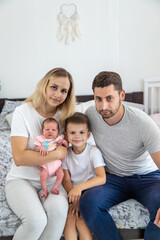 Obraz premium Portrait of a happy family with two children on bed