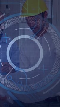 Helmeted lead leaning and reviewing held tablet while HUD overlay scanning plans for site review