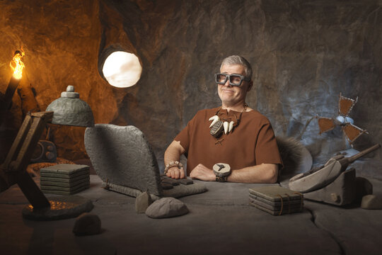 Business in the stone age: portrait of a businessman sitting at his desk