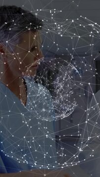 Vertical video: Doctor tapping tablet and causing 3D health network orb while nurse reviewing data